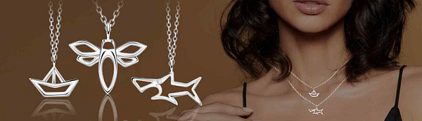 Minimal sterling silver outline necklaces with symbolic pendants including a boat, dragonfly and shark, styled as layered jewellery on a model, from an exclusive design collection created by SilverJD UK for jewellery retailers.